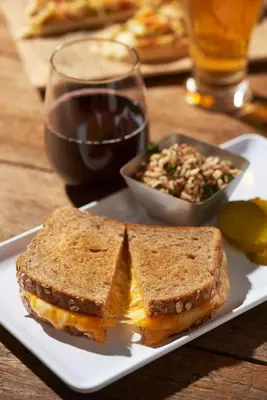 a sandwich on a plate with a salad and a glass of wine at Hyatt Place Denver Tech Center in Centennial