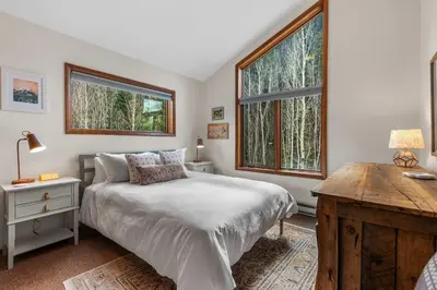 a bedroom with a bed and a desk and two windows at Keystone Gulch - Near Keystone Resort & Golf in Keystone