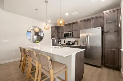 a kitchen with wooden cabinets and a kitchen island with chairs at The Landmark with Two King Beds, Garage and Fireplace in Fort Collins