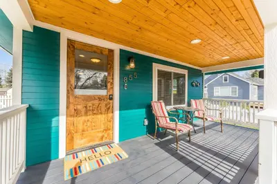 a blue house with a wooden door and chairs on a porch at Kanons Kottage Downtown Retreat Near RMNP in Loveland