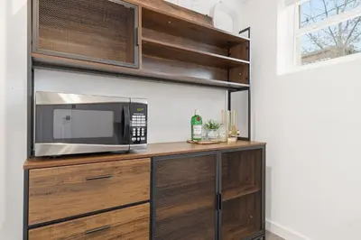 a microwave oven sitting on top of a wooden cabinet at Mathews House with 4 King Beds Near CSU and Old Town in Fort Collins