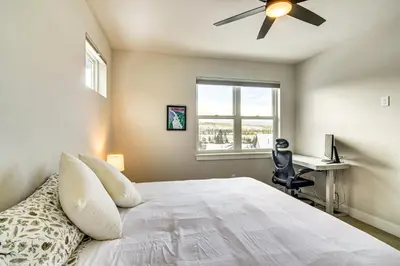 a bedroom with a bed with a ceiling fan and a desk at Saltwater Hot Tub! Unit Near Winter Park Slopes in Fraser