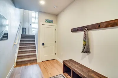 a hallway with a door and a bench and stairs at Saltwater Hot Tub! Unit Near Winter Park Slopes in Fraser