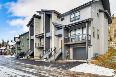 an apartment building with a garage on a street at Saltwater Hot Tub! Unit Near Winter Park Slopes in Fraser