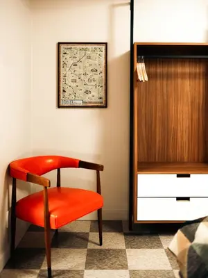 a red chair sitting next to a dresser in a room at La Vista Motel in Denver