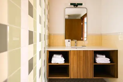 a bathroom with a sink and a mirror and towels at La Vista Motel in Denver