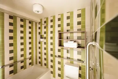 a bathroom with a green and white tiled wall at La Vista Motel in Denver