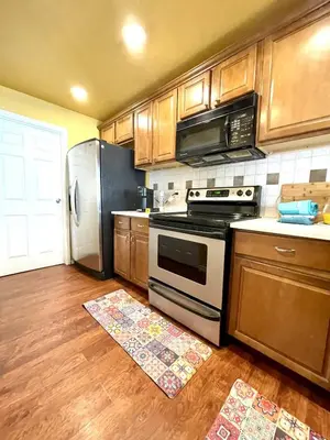 a kitchen with a stove and refrigerator and wooden cabinets at Townhome with Dedicated Workspace, WIFI, Garage in Lakewood