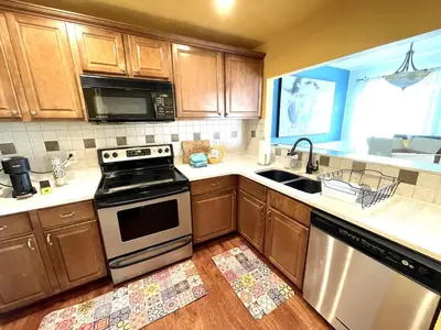 a kitchen with wooden cabinets and a stove and a sink at Townhome with Dedicated Workspace, WIFI, Garage in Lakewood