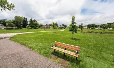 a park bench sitting in the grass next to a sidewalk at Townhome with Dedicated Workspace, WIFI, Garage in Lakewood