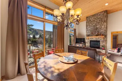 a dining room with a wooden table and a large window at Campfire Unit 13 in Keystone