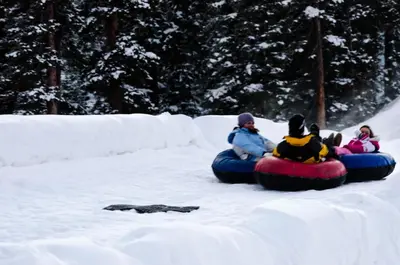 a group of people are riding on a tube in the snow at Snowdance 204A in Keystone