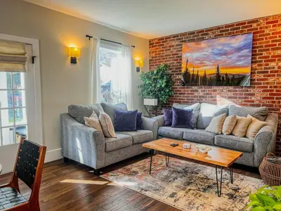 a living room with two couches and a brick wall at 9 Min Walk to Pearl Street - Downtown Boulder in Boulder