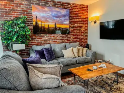 a living room with a couch and a brick wall at 9 Min Walk to Pearl Street - Downtown Boulder in Boulder