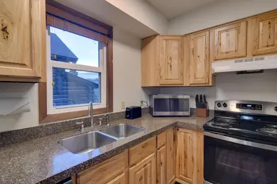 a kitchen with wooden cabinets and a sink and a window at Woodsy Winter Park Condo with Pool and Hot Tub Access in Winter Park