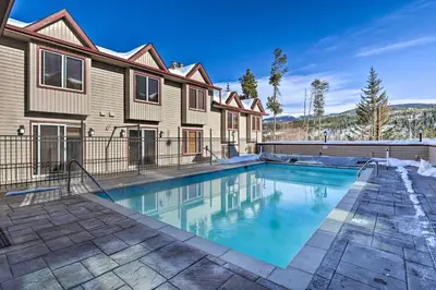 a swimming pool in front of a house at Woodsy Winter Park Condo with Pool and Hot Tub Access in Winter Park