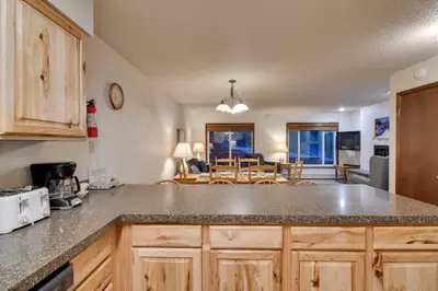 a kitchen with a counter top and a living room at Shuttle to Winter Park Resort! Group Condo with Pool in Winter Park