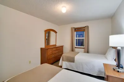a bedroom with two beds and a dresser and a mirror at Shuttle to Winter Park Resort! Group Condo with Pool in Winter Park