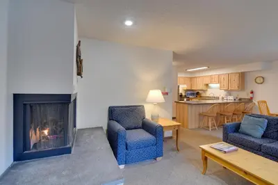 a living room with two chairs and a fireplace at Ski, Soak and Chill! Pool-View Winter Park Condo in Winter Park