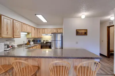 a kitchen with wooden cabinets and a counter top at 3 Mi to Skiing Walkable Dtwn Winter Park Condo! in Winter Park