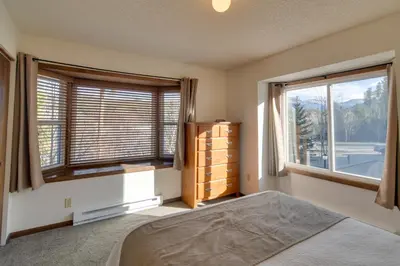 a bedroom with a bed and two large windows at Ski and Hike! Easy Adventuring at Winter Park Condo in Winter Park