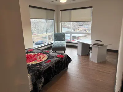a room with a bed and a desk and windows at Elegant Stay in Aurora