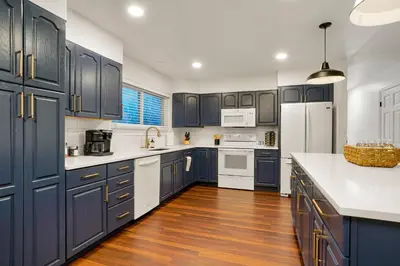 a kitchen with navy blue cabinets and white appliances at Family Fun Retreat - Hot Tub & Games in Arvada