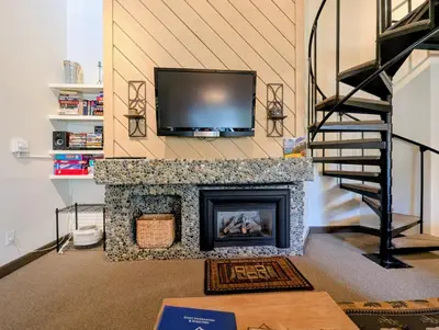 a living room with a fireplace with a tv above it at Flying Dutchman 1109 by SummitCove Lodging in Keystone