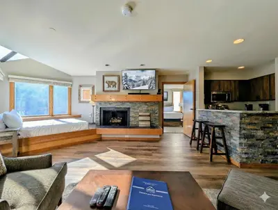 a living room with a bed and a fireplace at Lakeside 1491 by SummitCove Lodging in Keystone