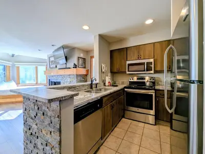 a kitchen with stainless steel appliances and wooden cabinets at Lakeside 1491 by SummitCove Lodging in Keystone