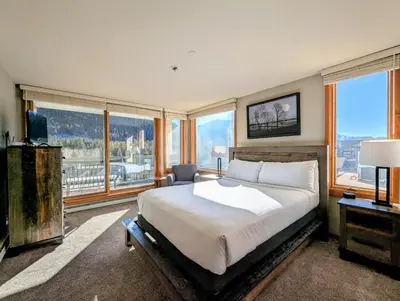 a bedroom with a large bed and large windows at Lakeside 1491 by SummitCove Lodging in Keystone