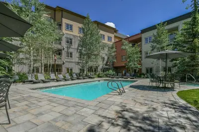 a swimming pool with chairs and tables and an umbrella at Expedition Station 8591 by SummitCove Lodging in Keystone