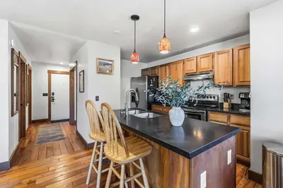 a kitchen with wooden cabinets and a island with chairs at 2BR Escape for 6 Overlooking Marina & Lake Dillon in Dillon