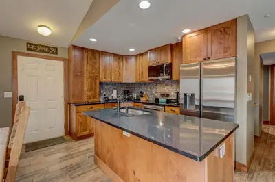 a kitchen with wooden cabinets and a stainless steel refrigerator at Breckenridge 2BR Ski and Mountain Adventure Base in Breckenridge