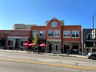 a brick building with tables and umbrellas on a city street at Beautiful Pearl Street condo! 30 DAY MINIMUM STAY in Boulder