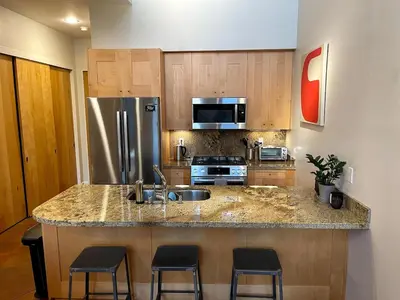 a kitchen with a sink and a counter with stools at Beautiful Pearl Street condo! 30 DAY MINIMUM STAY in Boulder
