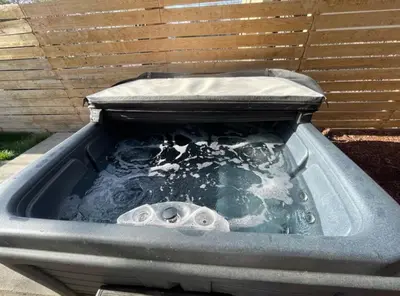 a bath tub filled with water in front of a fence at Lovely 2 bedroom unit with a hot tub Pet friendly in Denver