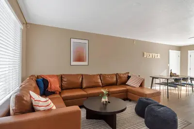 a living room with a brown couch and a table at 5 Bed/ Pickle360/ Basketball/ Movie in Thornton