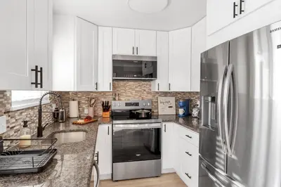 a kitchen with white cabinets and a stainless steel refrigerator at 5 Bed/ Pickle360/ Basketball/ Movie in Thornton