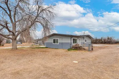 a small white house with a tree in a field at 3 Mi to Dtwn Berthoud Home with Longs Peak Views in Berthoud