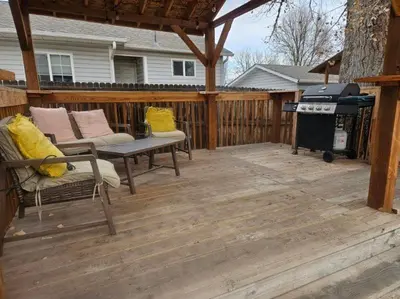 a patio with a grill and chairs on a wooden deck at 3BR Lakewood • Free Parking + BBQ • Near Red Rocks in Lakewood