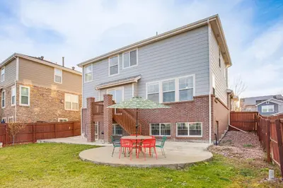a table with chairs and an umbrella in front of a house at Spacious Family Home at Buckley SFB with Patio! in Aurora