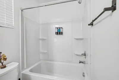 a white bathroom with a tub and a toilet at Modern 2BR 2BA Townhome 15 Min to DEN in Commerce City