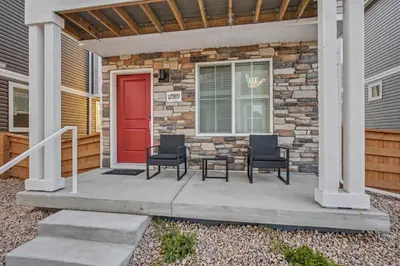 a front porch with chairs and a red door at Modern 2BR 2BA Townhome 15 Min to DEN in Commerce City