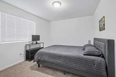a white bedroom with a bed and a window at Modern 2BR 2BA Townhome 15 Min to DEN in Commerce City