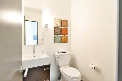 a bathroom with a toilet and a sink and a mirror at You Are My Sunshine - Downtown Frisco Home in Frisco
