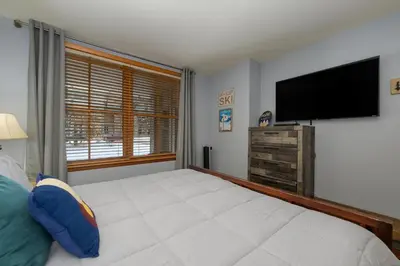 a bedroom with a bed and a flat screen tv at Premium Unit 1100 - One Bedroom - Zephyr Mountain Lodge condo in Winter Park