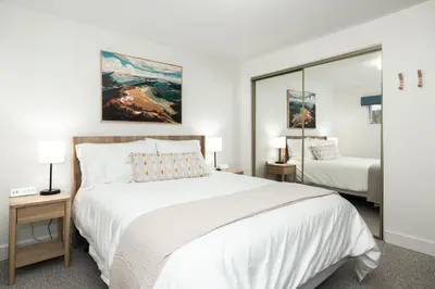 a bedroom with a large white bed and a mirror at Cozy Winter Park Ski & Bike Retreat in Winter Park