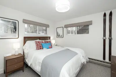 a white bedroom with a bed and two windows at Cozy Winter Park Ski & Bike Retreat in Winter Park