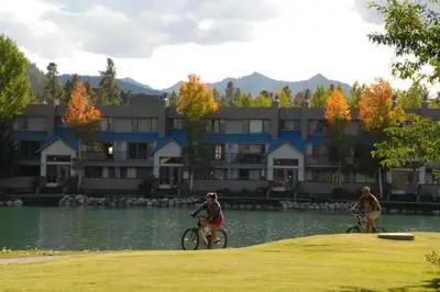two people riding bikes by the water in front of a building at Lakeshore 1535 in Keystone